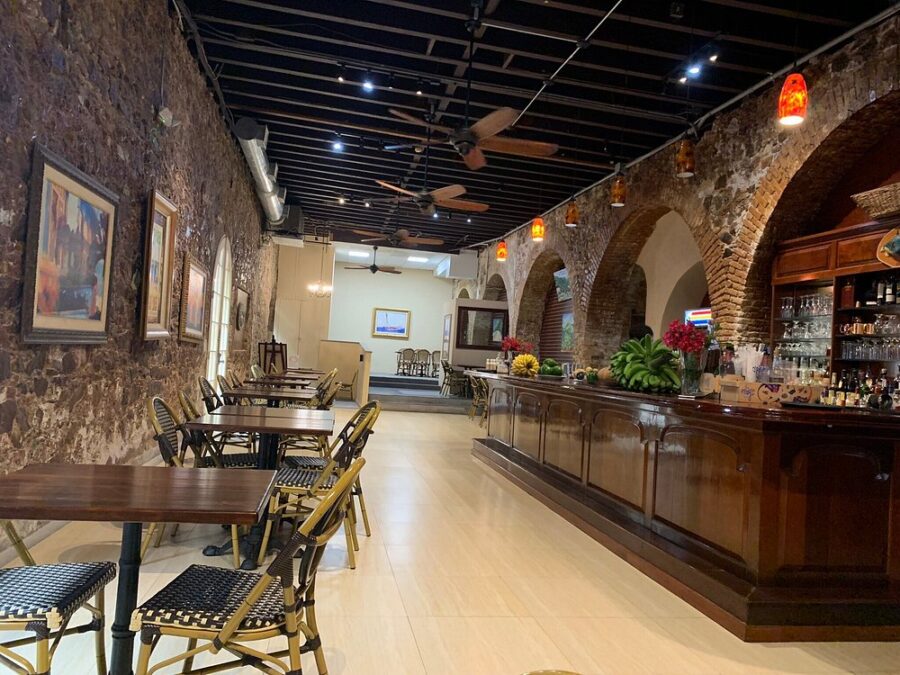 Gladys’ Café St Thomas with tables and chairs arranged in front of a textured brick wall, creating a cozy dining atmosphere.
