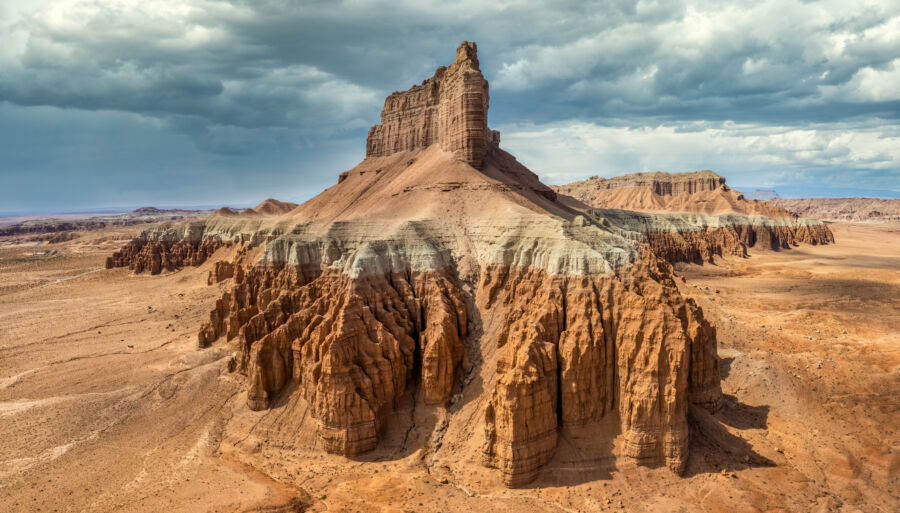 Goblin Valley State Park features unique sandstone formations and a rugged mesa under a dramatic, cloudy sky.