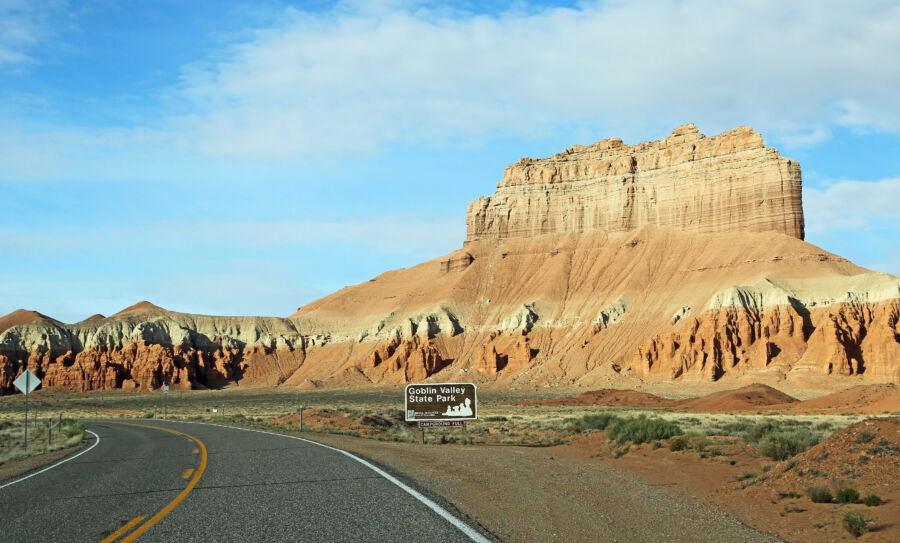 Scenic view of a winding road through Goblin Valley, Utah, surrounded by unique rock formations and desert landscape.