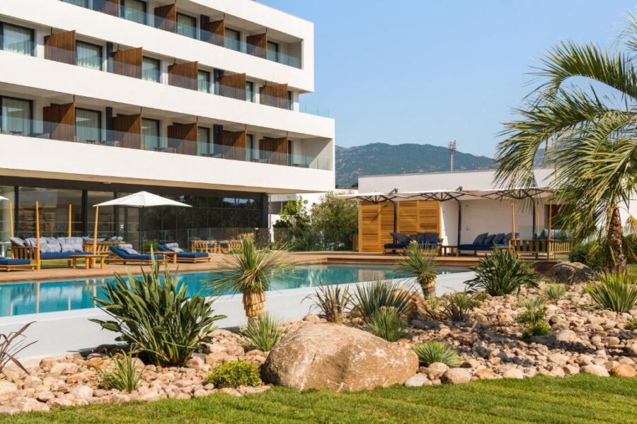 Pool and lounge chairs at Golden Tulip Porto-Vecchi, Corsica, France, inviting relaxation in a sunny setting.