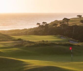 Scenic golf course at coastal sunset with lush greens and tranquil sea view.