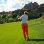 Golfer mid-swing on lush course