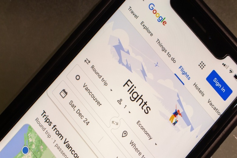 Smartphone displaying Google Flights search interface with Vancouver departure, round-trip options, and travel date.