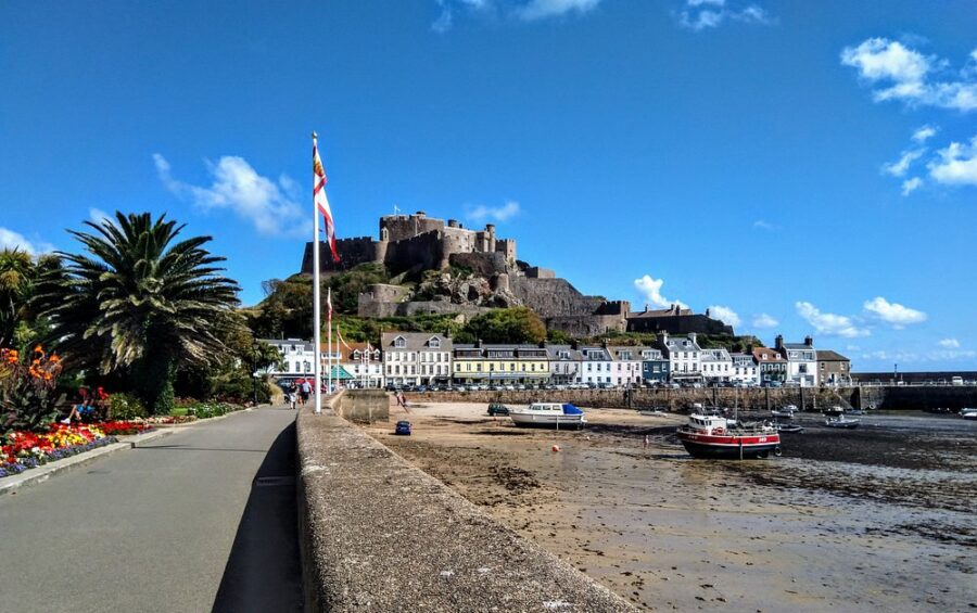 Scenic view of a castle on a hill above Gorey Harbour, with the sea stretching out in the background in the Channel Islands.