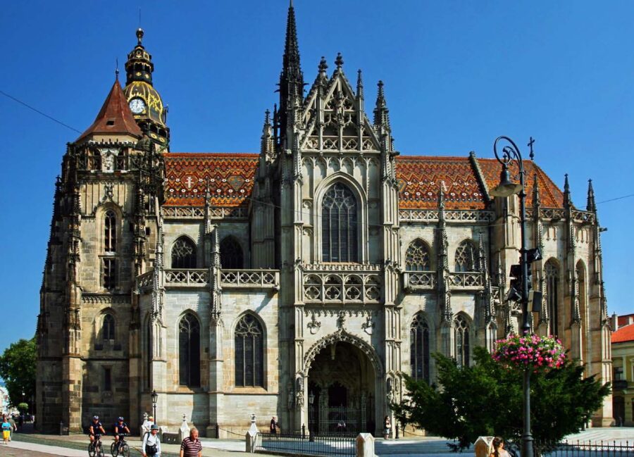 Gothic St. Elisabeth Cathedral with ornate facade, clock tower, and colorful tiled roof in plaza.
