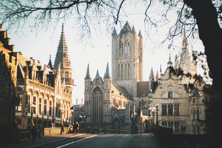 Ghent, Belgium Gothic cathedral on cobblestone avenue at golden hour.