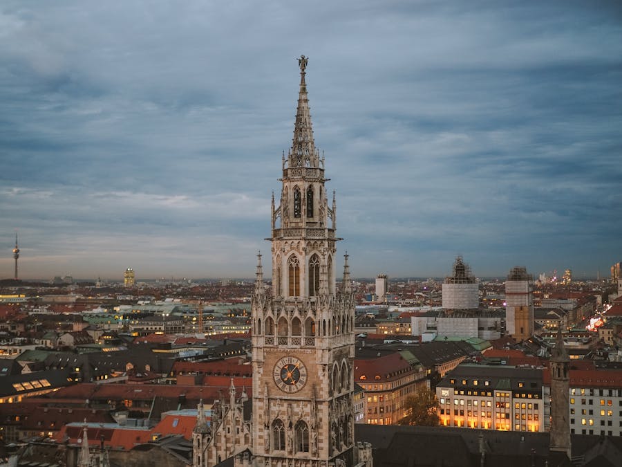 Gothic clock tower rising above historic city skyline at dusk.