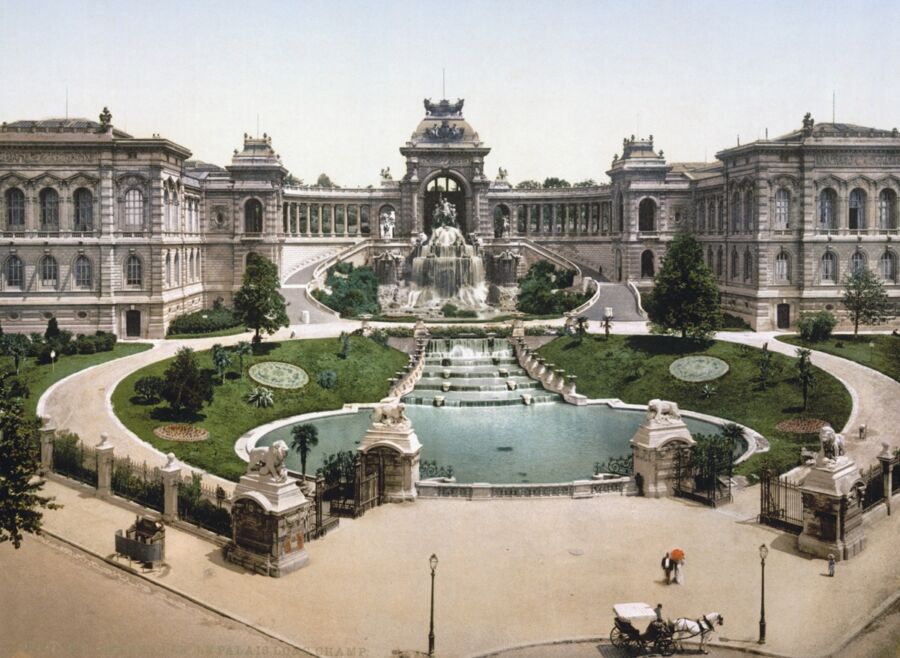 Neoclassical architecture with fountain, gardens, sculptures, and horse-drawn carriage in an urban park.