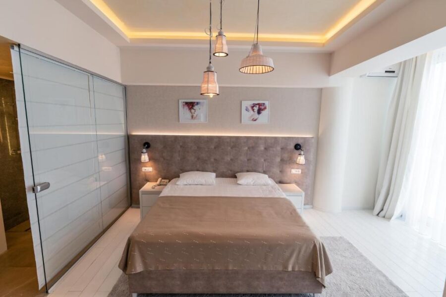Interior of a bedroom at Grand Hotel Belvedere, Brasov, showcasing a comfortable bed and a stylish light fixture.