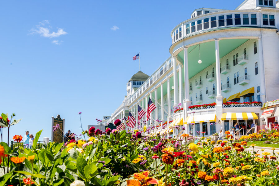 Grand Hotel summer garden resort with colorful flowers, historic white veranda, and American flags.