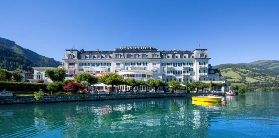 The Grand Hotel Zell am See in Austria overlooks the lake, featuring a boat gently bobbing in the water.
