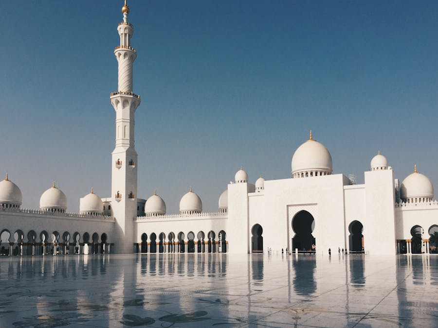 Sheikh Zayed Grand Mosque with marble minaret and gold domes against clear blue sky.