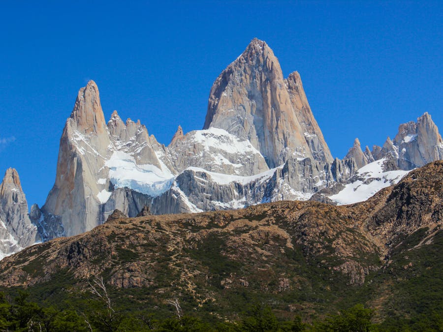 Dramatic granite spires of Mount Fitz Roy in Patagonia with snow-covered peaks and rugged cliffs.