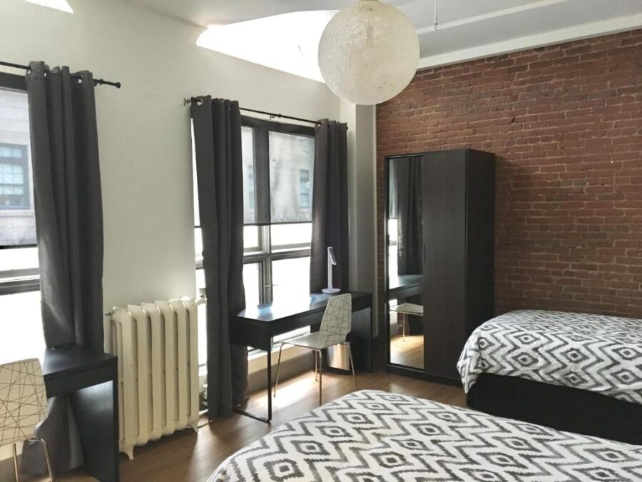 Interior of a Granville Hall Residence bedroom with a bed, desk, and a window, creating a cozy living space.