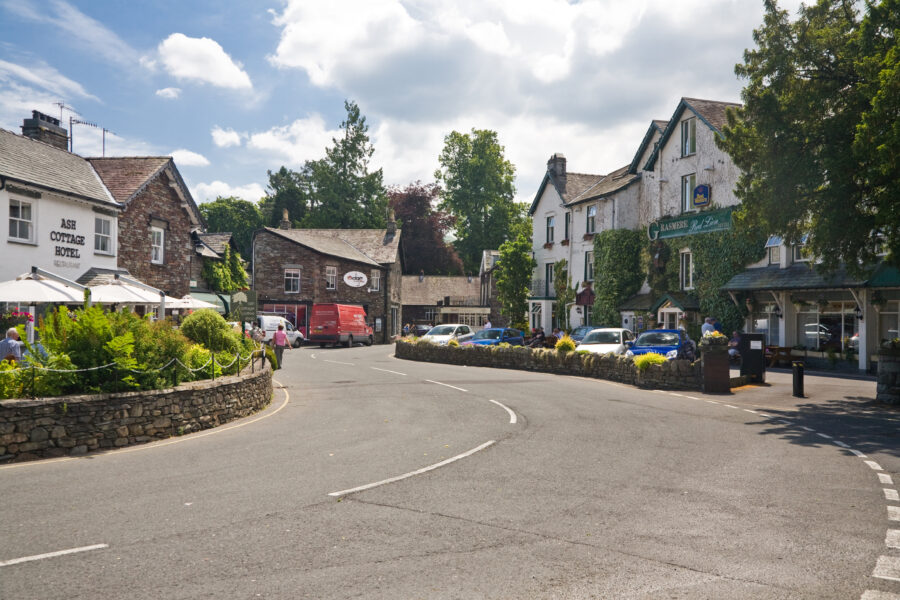 White road marked with white lines runs through Grasmere, a picturesque village in Cumbria, Lake District, England.