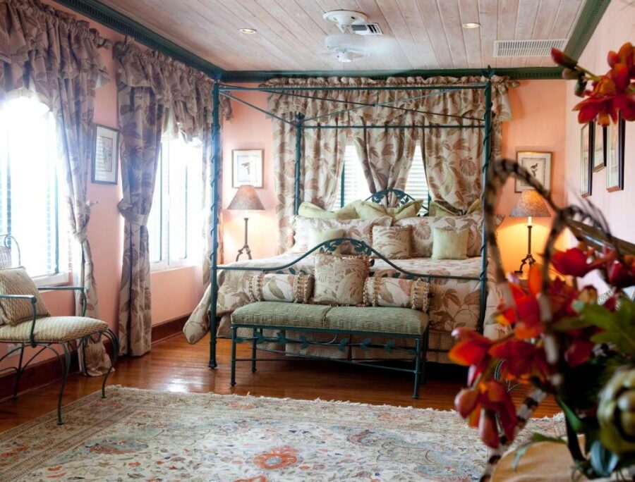 Elegant bedroom with a four-poster bed and a colorful floral arrangement, located in Graycliff Hotel, Nassau, Bahamas.