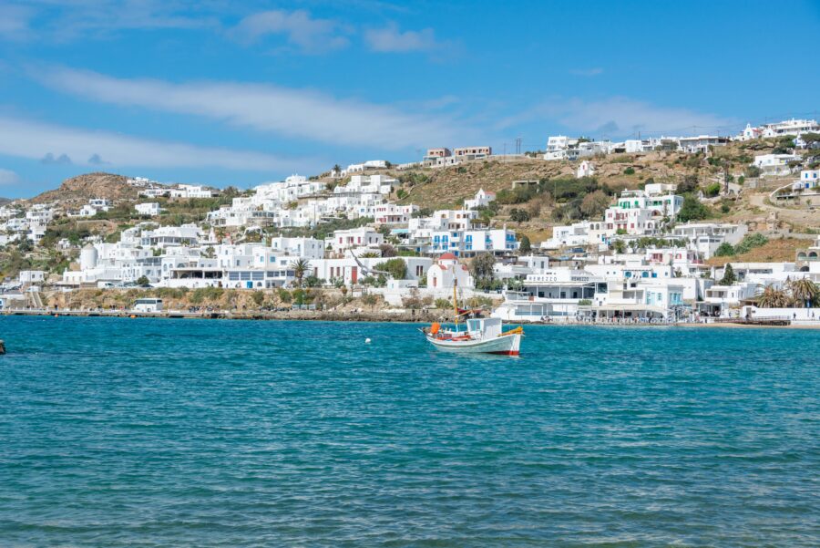 Stunning Greek island coastal scene with blue waters, whitewashed buildings, and colorful boats.