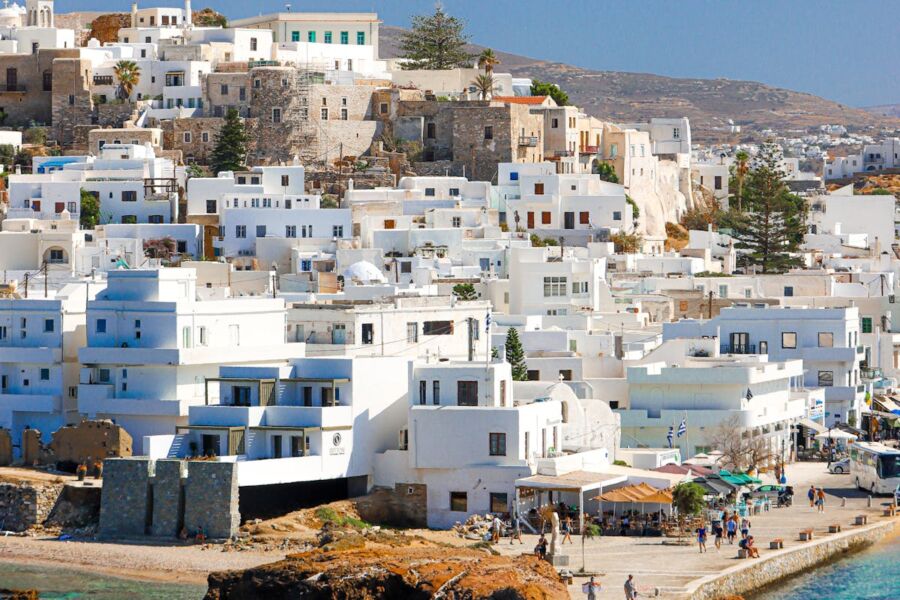Picturesque Greek island coastal village with whitewashed buildings, cafes, and Mediterranean sea views.