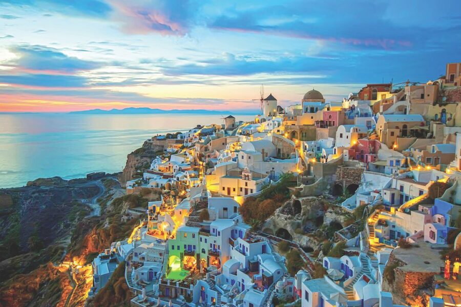 Cycladic village at sunset with whitewashed buildings, Aegean Sea, and windmill.