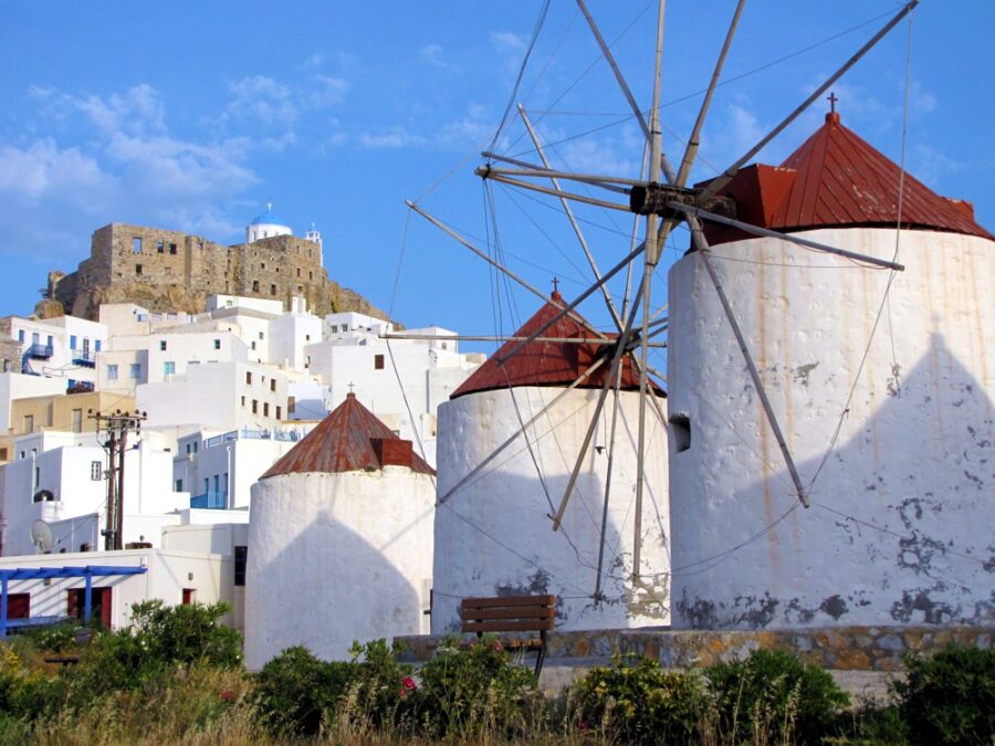 Greek island windmills, white architecture, blue skies, vibrant flowers, serene and picturesque.
