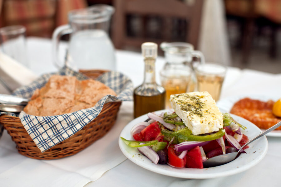 Greek salad served with rustic country bread and a glass of homemade white wine