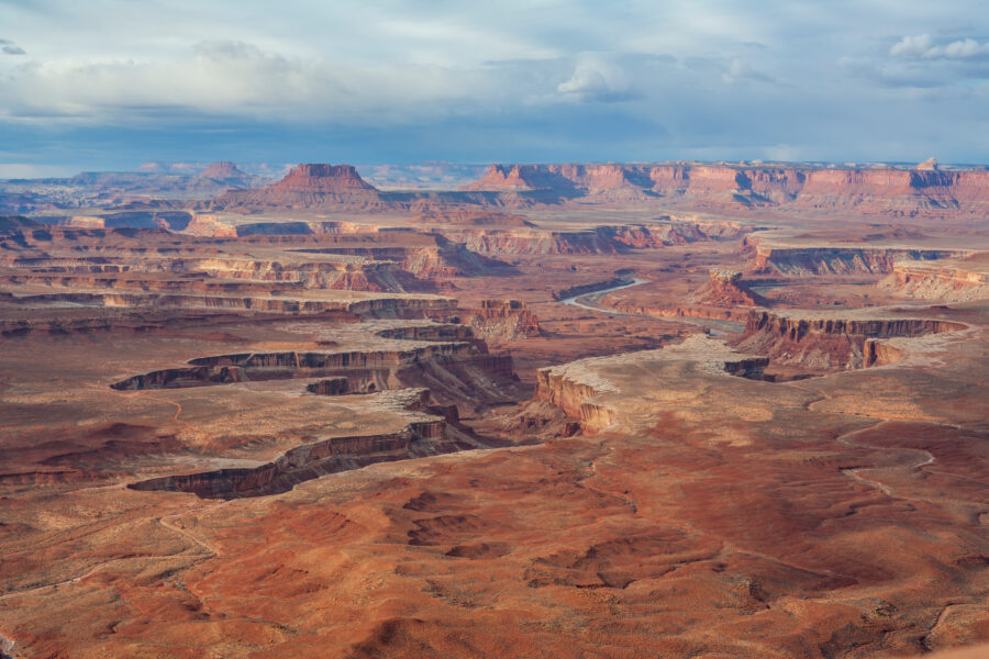 Expansive view of the Green River winding through the rugged canyons of Canyonlands National Park under a clear blue sky.