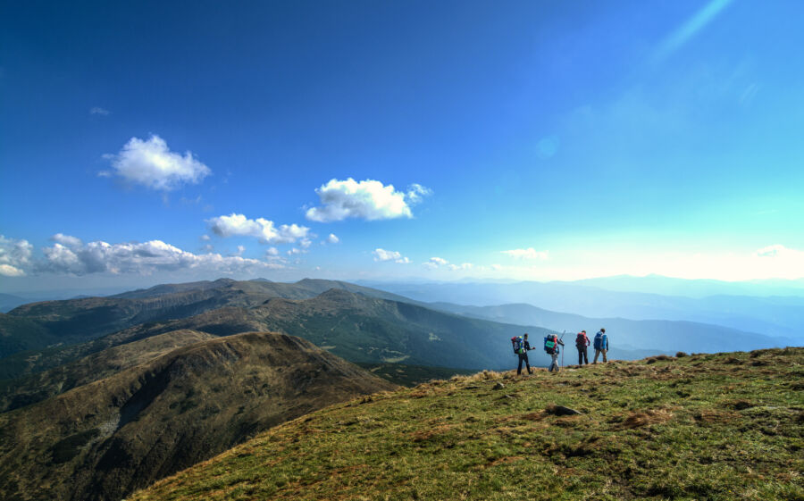 Travelers with backpacks trek through the mountains, surrounded by stunning natural scenery
