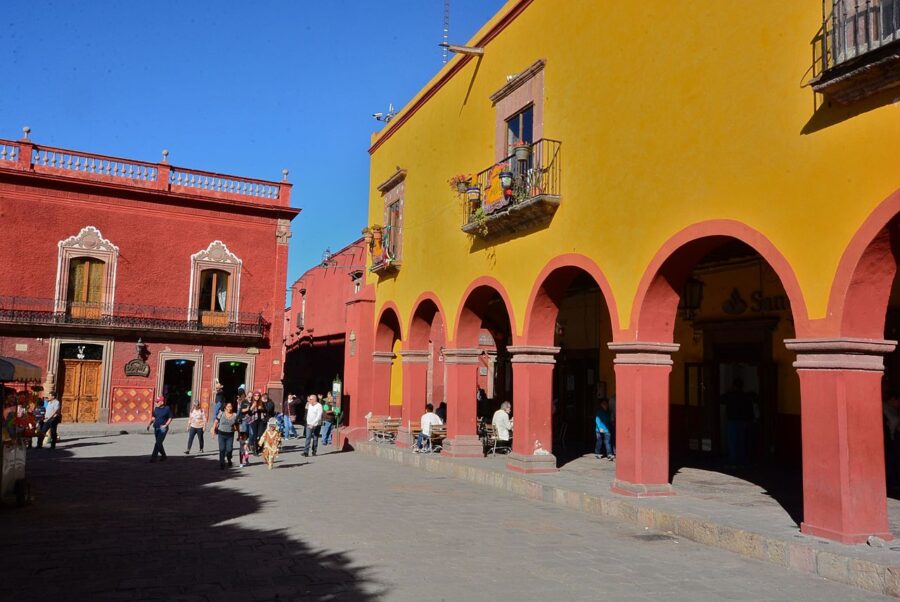 People walk together in a lively plaza in Guadalupe, San Miguel de Allende, showcasing the city's cultural atmosphere.
