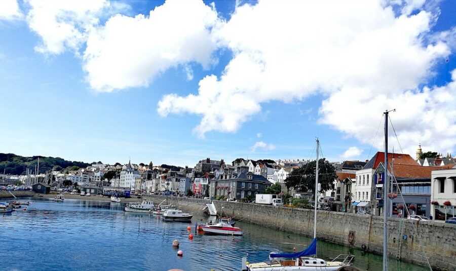 Guernsey's picturesque harbor with various boats and waterfront houses reflecting the coastal charm of the UK