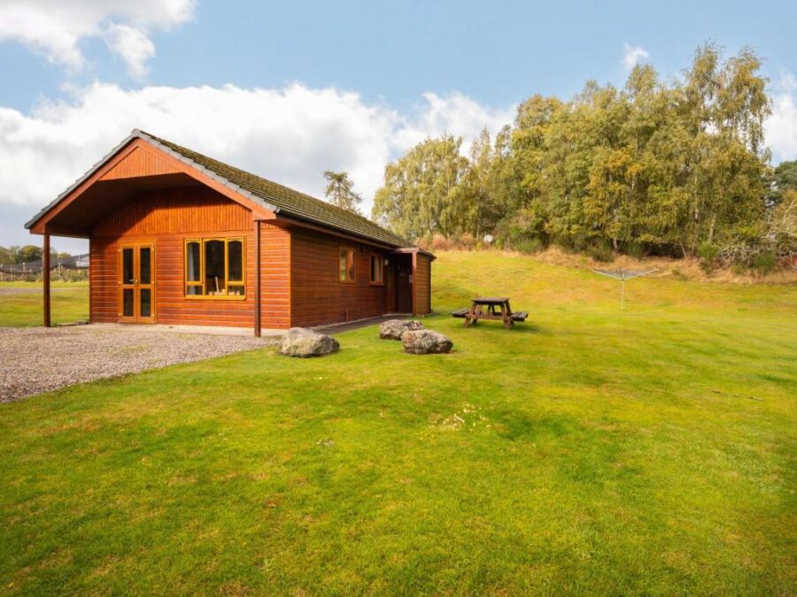 Guisachan Lodge cabin nestled in a lush grassy field, showcasing a serene natural setting.