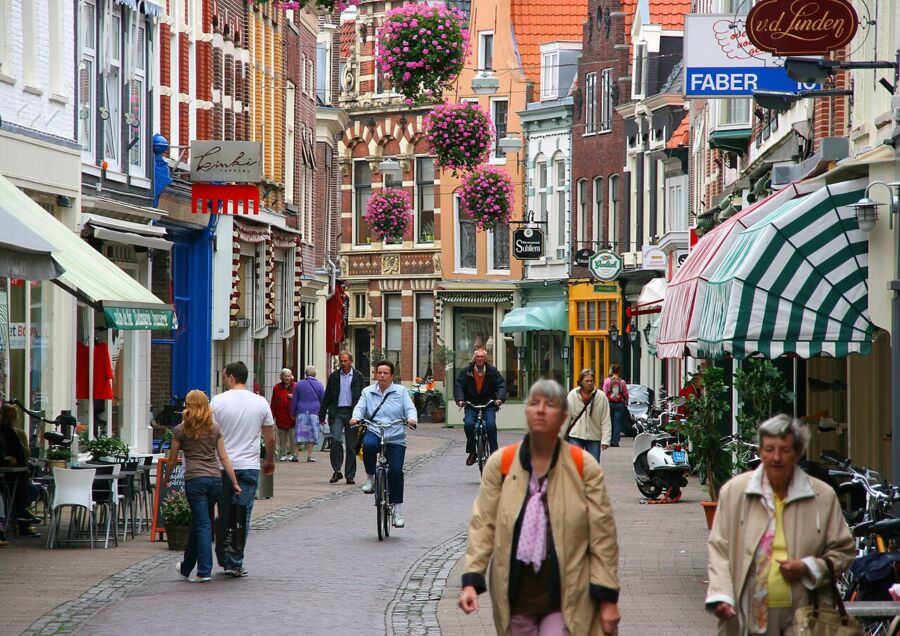 Several individuals stroll down a lively street in Haarlem, Netherlands, showcasing the city's vibrant atmosphere and architecture.