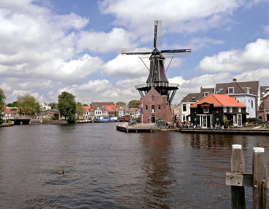 Classic windmill is located next to a calm waterway in Haarlem, Netherlands, showcasing the region's scenic beauty.