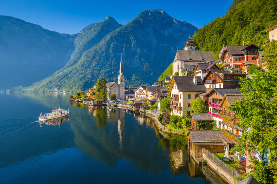 Scenic summer view of Hallstatt, Austria, showcasing its charming buildings and lush green mountains surrounding the lake