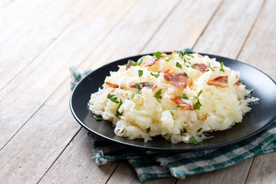 Plate of Slovak halusky potato dumplings with sauerkraut and bacon on a wooden table