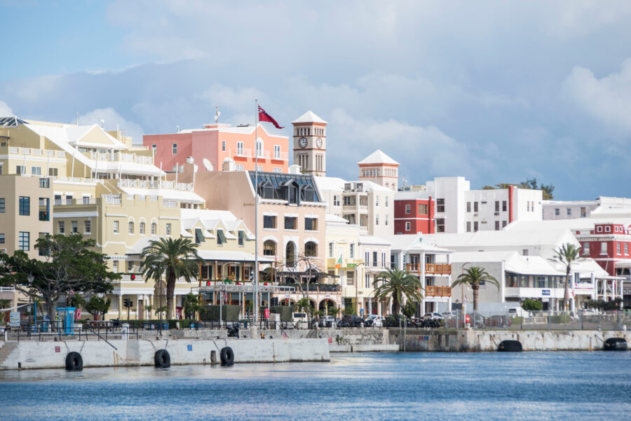 Panoramic image of Hamilton, Bermuda, featuring the waterfront, pastel-colored architecture, and lush greenery