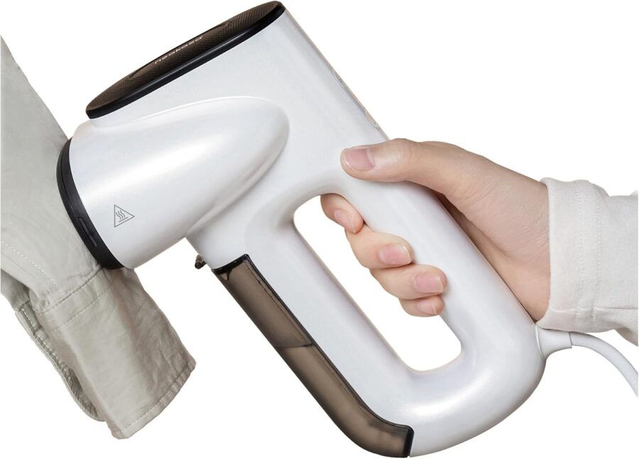 Handheld garment steamer steaming shirt cuff, electric wrinkle remover with ergonomic handle.