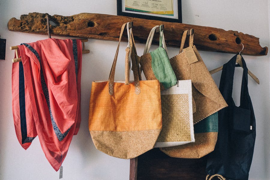 Handmade sustainable bags and scarf displayed on wooden shelf in artisan-style boutique.