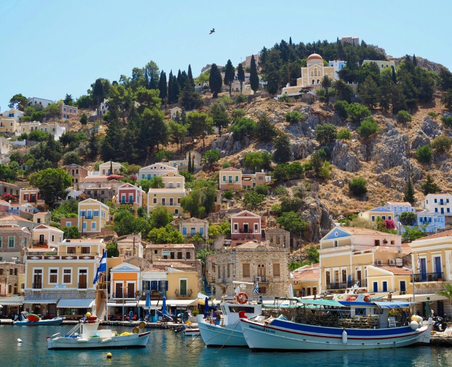 Mediterranean Symi, Greece harbor with pastel hillside houses and moored fishing boats.