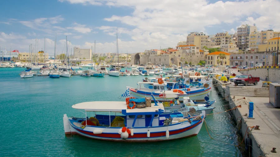 Heraklion harbor with fishing boats on turquoise Mediterranean water.
