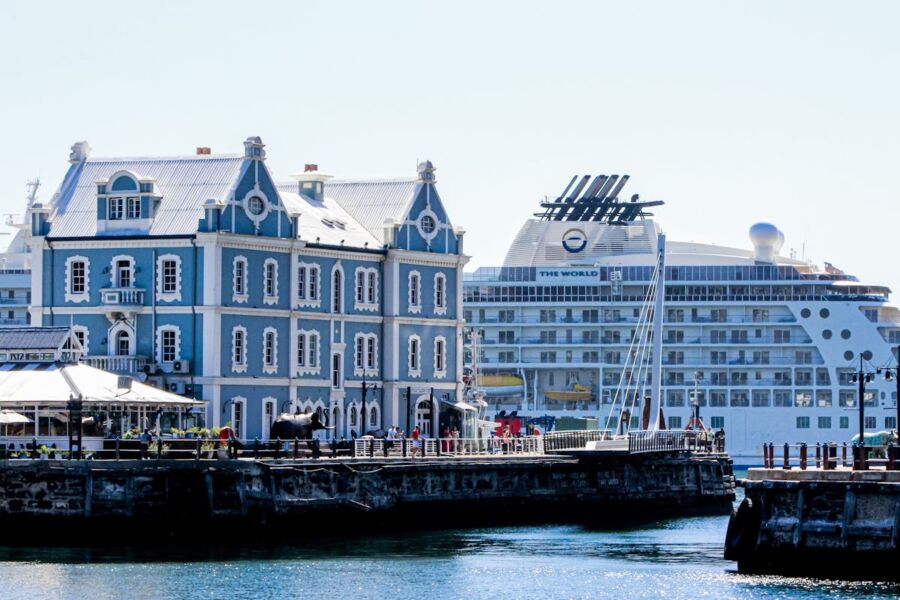 Harbor scene with historical architecture, cruise ship, and lively waterfront activities.