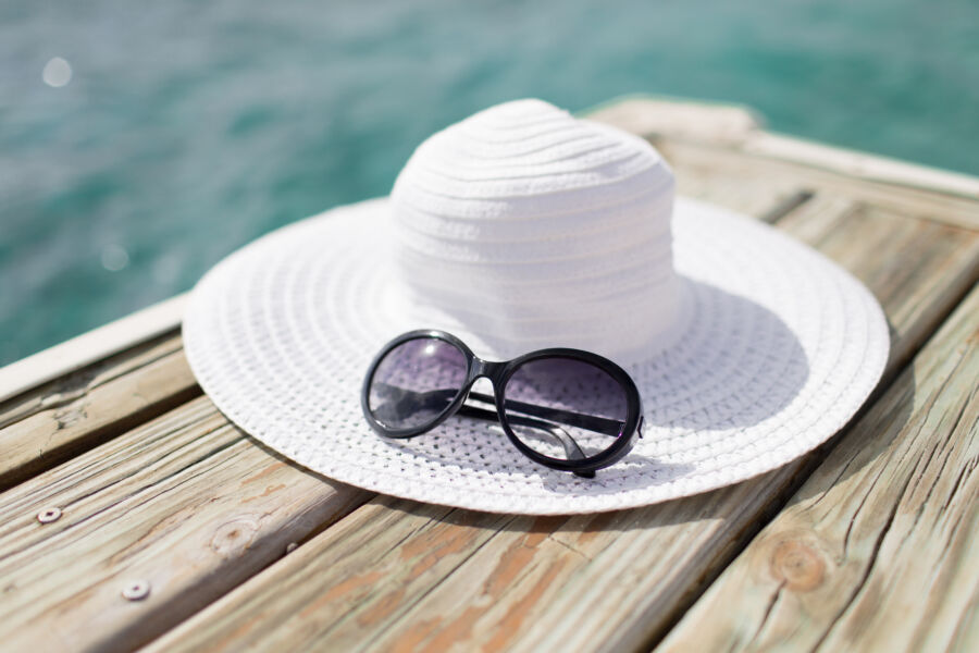 Close-up of a fashionable hat and sunglasses placed on the sand, capturing the essence of a seaside getaway