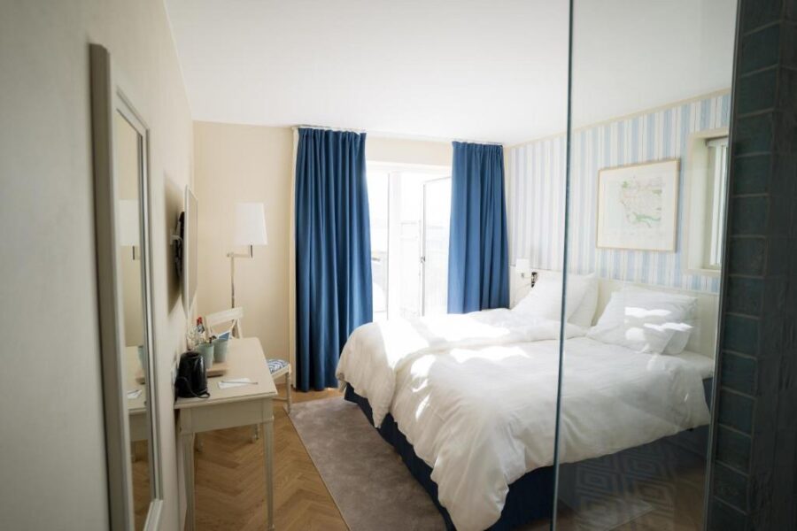 Interior of a bedroom with a bed, shower, and mirror, located in Havgrim Seaside Hotel, established in 1948, Faroe Islands.