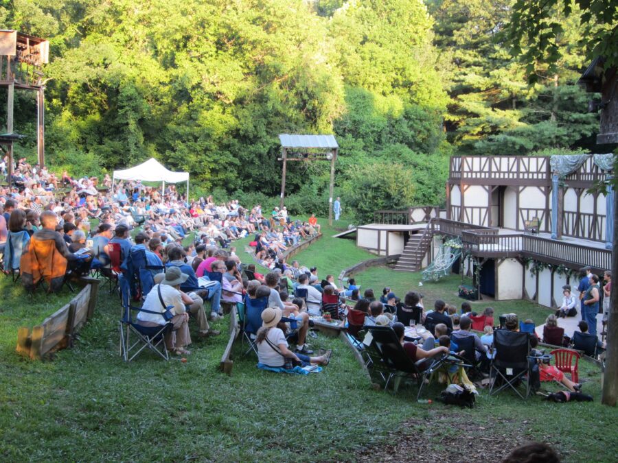 People gather on lawn chairs at Hazel Robinson Amphitheatre, soaking up the sun in a vibrant park setting.