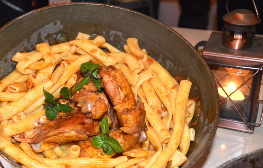 Rustic pasta dish with tender meat, rich sauce, and fresh basil in a cozy setting.