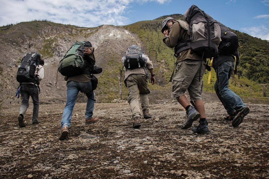 Group of hikers ascending a rugged slope with backpacks and trail gear.