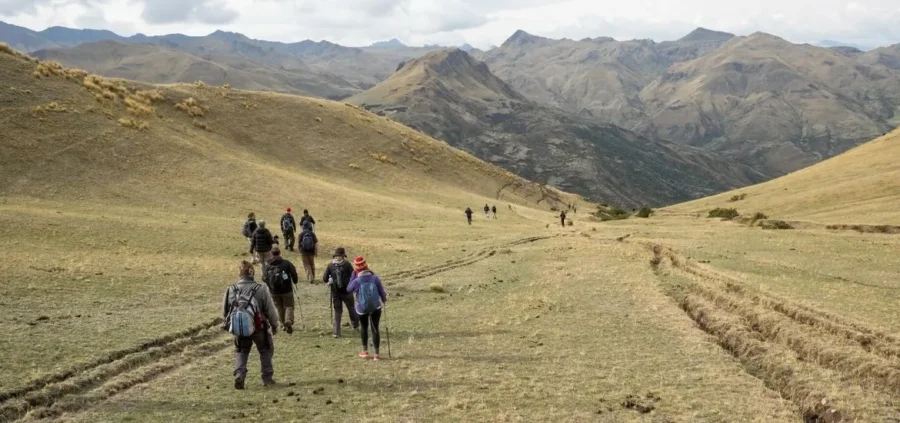 Hikers on scenic mountainous trail amidst clouds and rugged peaks, exploring high-altitude beauty.