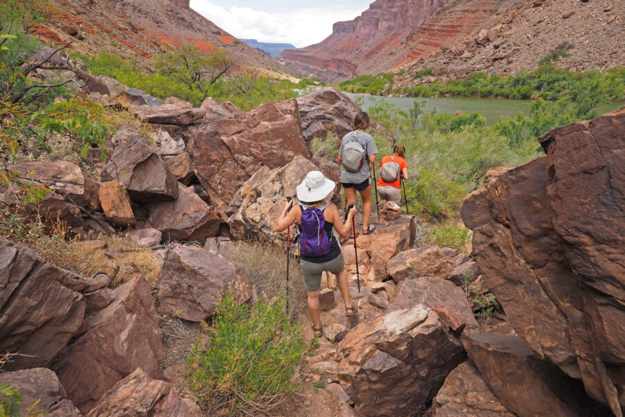 Group of hikers on a trail next to the Colorado River, with Hance Rapids visible in the Grand Canyon, Arizona