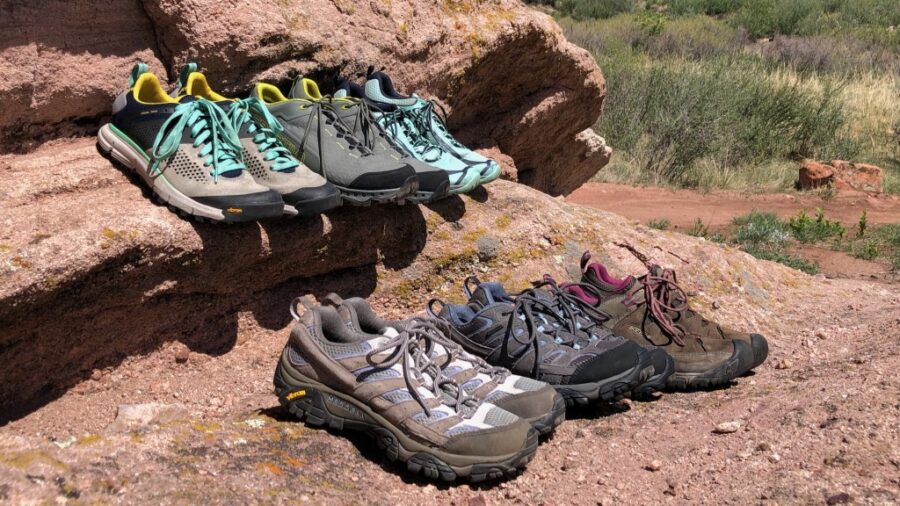Outdoor hiking shoes on rugged rock, showcasing diverse styles and colors for trail adventures.