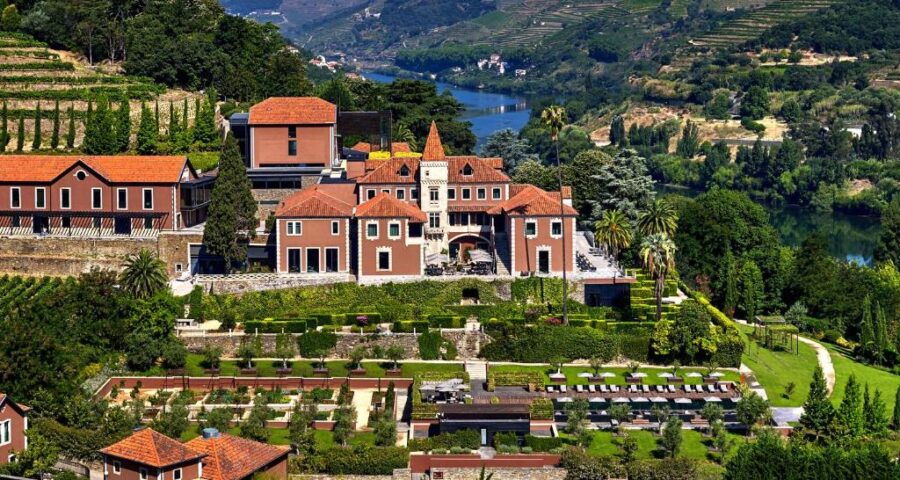 Elegant estate nestled in lush vineyard landscape by serene river and rolling hills.
