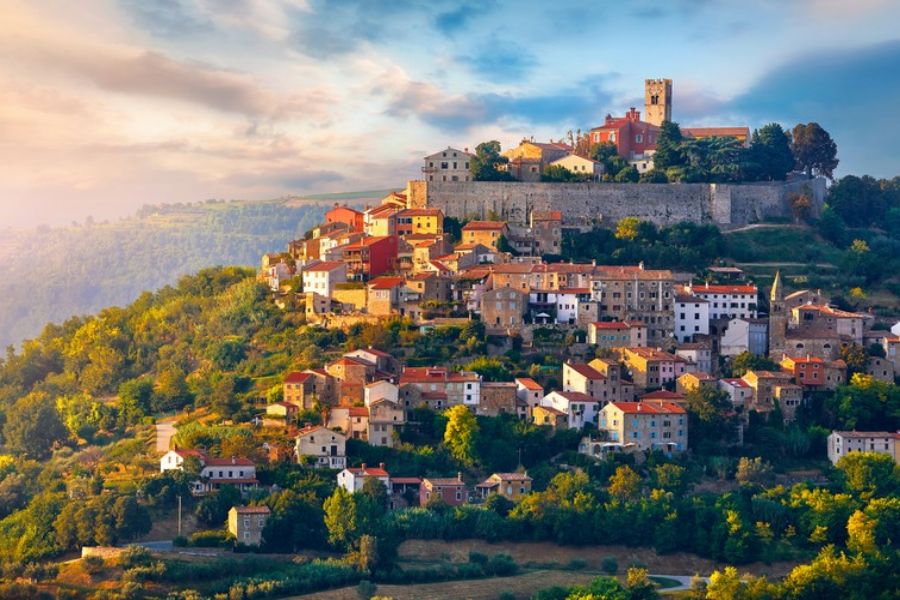 Picturesque Motovun village at sunset: charming architecture, stone walls, lush hills, vibrant sky.